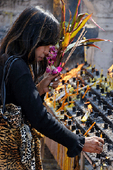 mujer poniendo velas en un templo de Lampang
